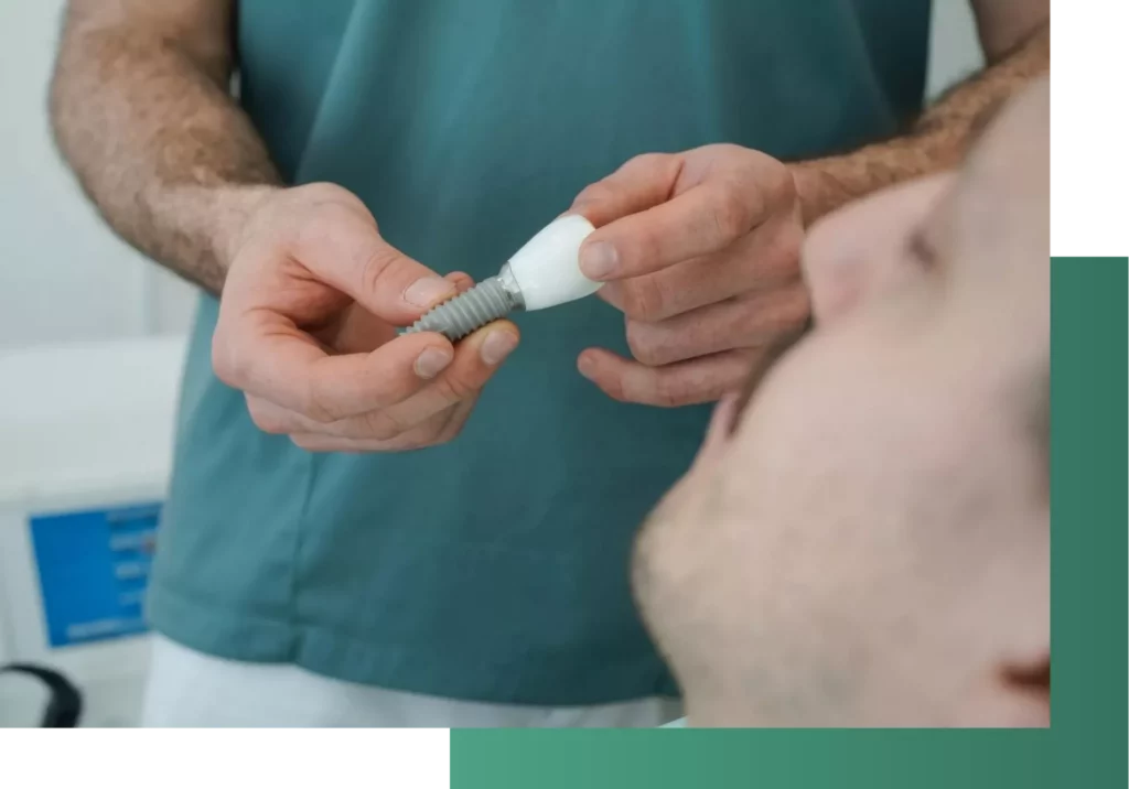 Zahnarzt zeigt Implantat dem Patienten.